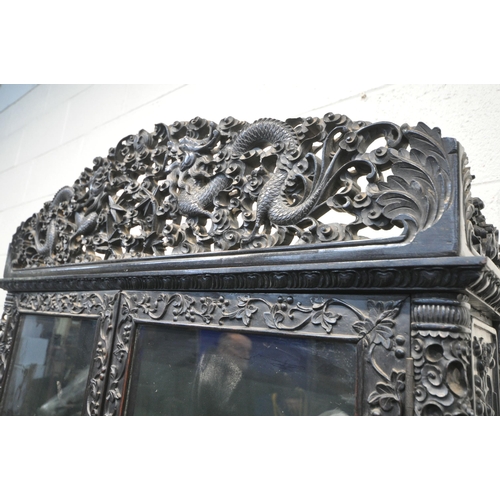 1353 - A 19TH CENTURY EBONISED ROSEWOOD CHINESE BOOKCASE ABOVE DESK, heavily carved throughout with dragons... 