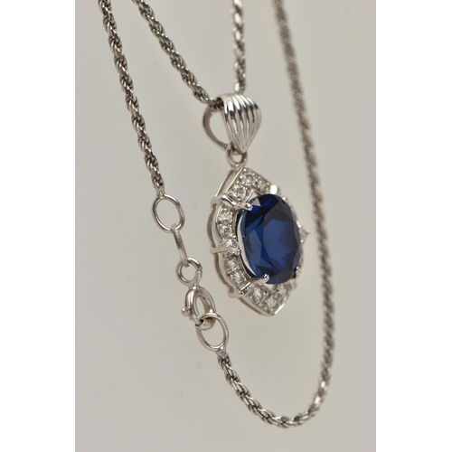 80 - A WHITE METAL PENDANT NECKLACE, the pendant set with an oval cut synthetic blue sapphire in a surrou... 