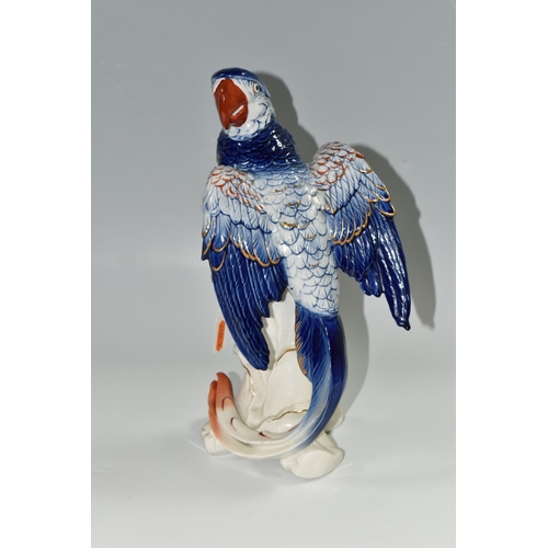 345 - A KARL ENS PORCELAIN 'MACAW' FIGURE, perched on top of a branch, blue and red gilt decoration, impre... 