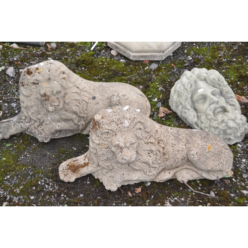 1004 - A PAIR OF COMPOSITE RECLINED GARDEN LIONS, length 72cm, along with a composite Zeus head figure, etc... 