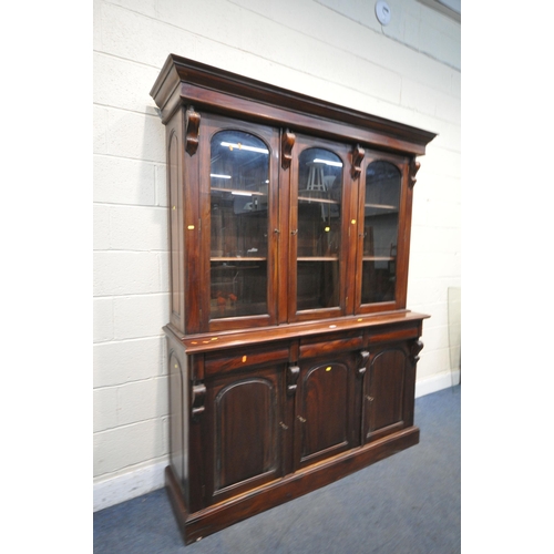 1209 - A VICTORIAN STYLE MAHOGANY GLAZED THREE DOOR BOOKCASE, over a base with three drawers and cupboard d... 