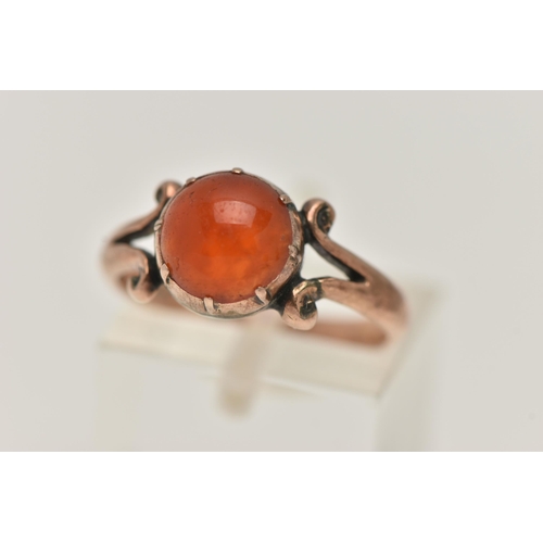 19 - A ROSE METAL CARNELIAN RING, set with a circular cut carnelian cabochon, claw set, bifurcated scroll... 