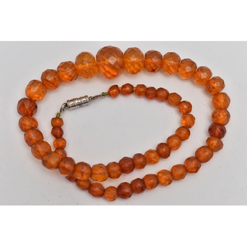 29 - A GRADUATED FACETED COPAL AMBER BEAD NECKLACE, fitted with a white metal magnetic clasp, length 440m... 