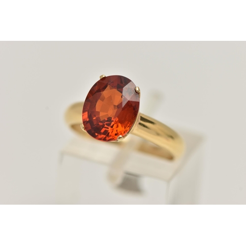 82 - A GEM SET RING, oval cut orange stone, assessed as spessartine garnet, prong set in yellow metal, st... 