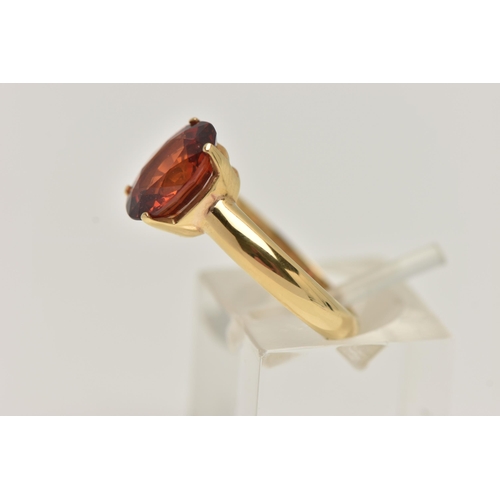 82 - A GEM SET RING, oval cut orange stone, assessed as spessartine garnet, prong set in yellow metal, st... 