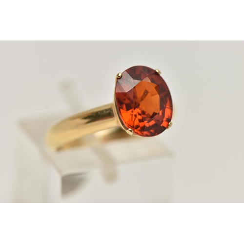 82 - A GEM SET RING, oval cut orange stone, assessed as spessartine garnet, prong set in yellow metal, st... 