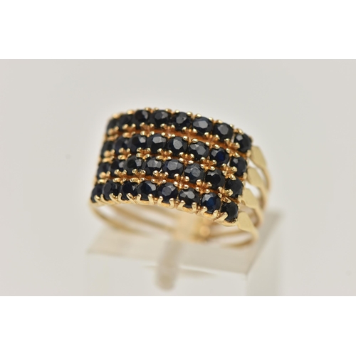 84 - A FOUR ROW GEM SET RING, thirty two circular cut dark blue sapphires, prong set in yellow metal, sta... 