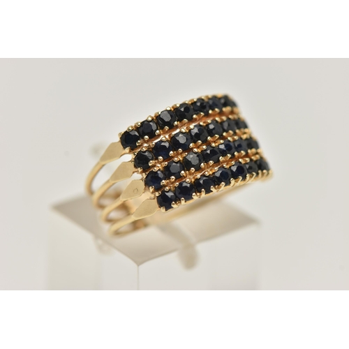 84 - A FOUR ROW GEM SET RING, thirty two circular cut dark blue sapphires, prong set in yellow metal, sta... 