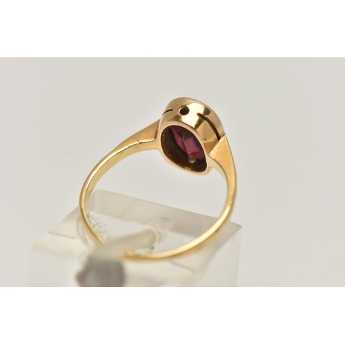 9 - A YELLOW METAL GARNET RING, set with an oval cut garnet, collet set to a polished band, stamped 18ct... 