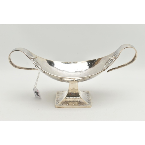 96 - A GEORGE V PLANISHED SILVER ARTS AND CRAFTS TWIN HANDLED OVAL PEDESTAL BOWL, the elongated scroll ha... 