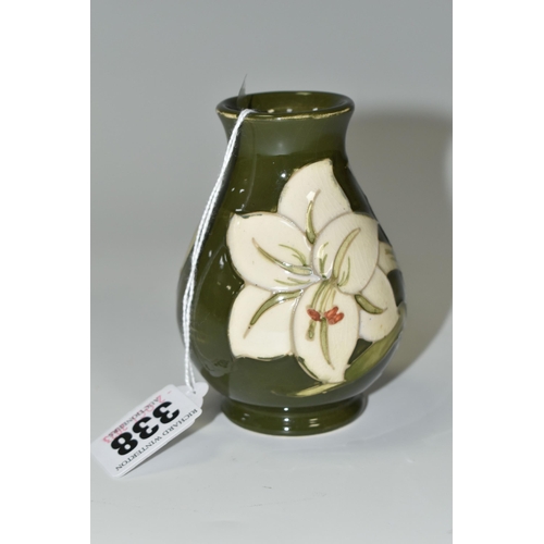 338 - A MOORCROFT POTTERY BALUSTER VASE DECORATED WITH WHITE LILIES ON A GREEN GROUND, impressed marks and... 