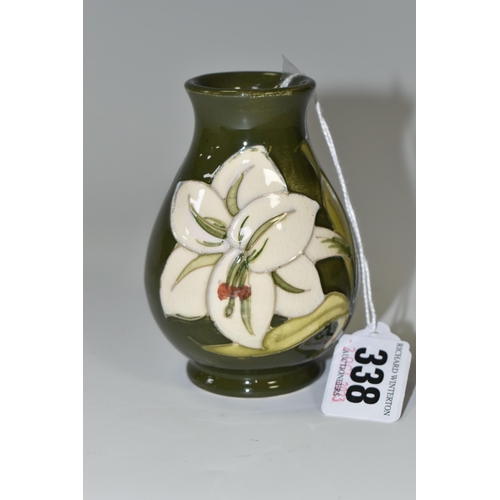 338 - A MOORCROFT POTTERY BALUSTER VASE DECORATED WITH WHITE LILIES ON A GREEN GROUND, impressed marks and... 