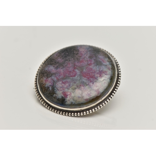 70A - A WHITE METAL RUSKIN BROOCH, of a circular form, painted ceramic insert, signed to the reverse Ru... 