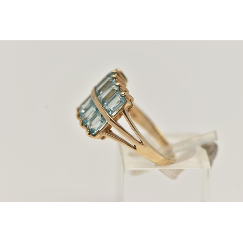 25 - A 9CT GOLD TOPAZ DRESS RING, designed with two rows of rectangular cut light blue topaz, trifurcated... 