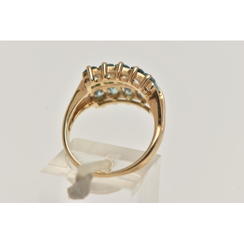 25 - A 9CT GOLD TOPAZ DRESS RING, designed with two rows of rectangular cut light blue topaz, trifurcated... 