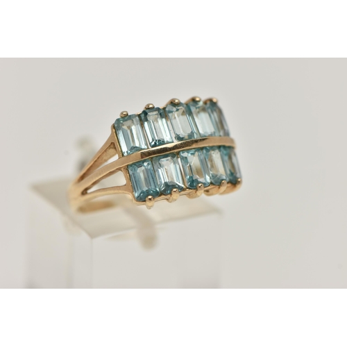 25 - A 9CT GOLD TOPAZ DRESS RING, designed with two rows of rectangular cut light blue topaz, trifurcated... 