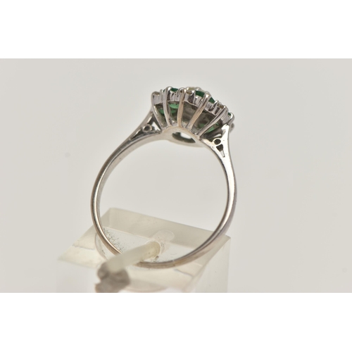 27 - A WHITE METAL EMERALD AND DIAMOND CLUSTER RING, circular cluster, set with a central raised round br... 