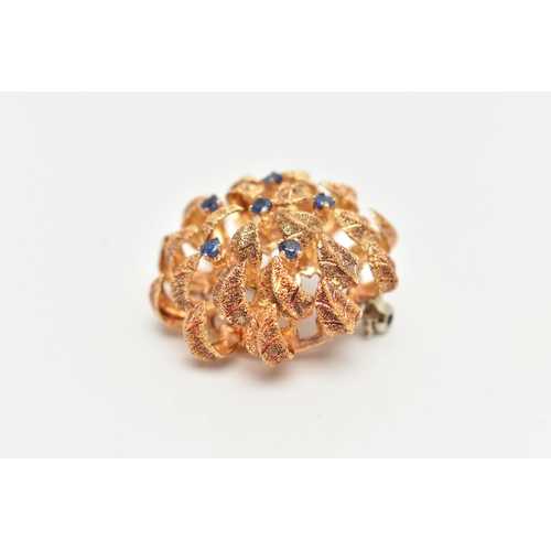 116 - A 14CT GOLD BROOCH, circular textured dome leaf brooch, set with six small circular cut blue sapphir... 