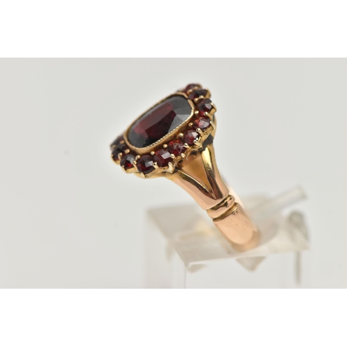 121 - AN EDWARDIAN 18CT GOLD GARNET RING, designed as a rectangular shape garnet within a circular cut gar... 