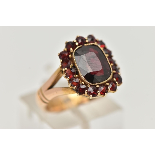 121 - AN EDWARDIAN 18CT GOLD GARNET RING, designed as a rectangular shape garnet within a circular cut gar... 