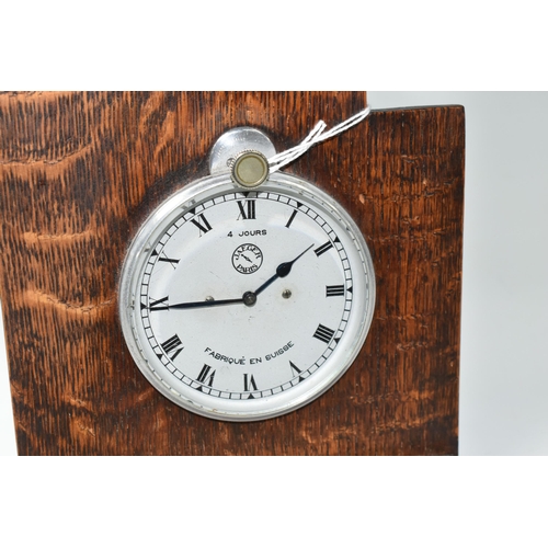 514 - A JAEGER FOUR DAY CAR CLOCK, fitted into an oak mount, the silver coloured dial having Roman numeral... 