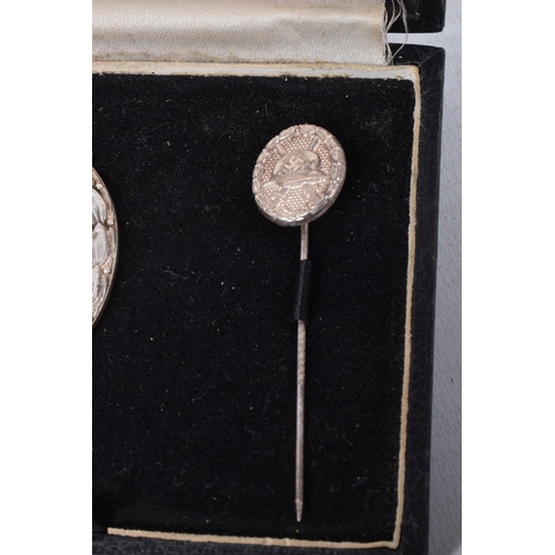 411 - A GERMAN WWII ERA SILVER WOUND BADGE WITH A SIMILAR STICK PIN, the badge is solid backed and has a m... 