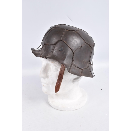 469 - A BATTLE DAMAGED WWII ERA GERMAN STEEL HELMET WITH CAMOUFLAGE WIRE NETTING,  this helmet still has a... 