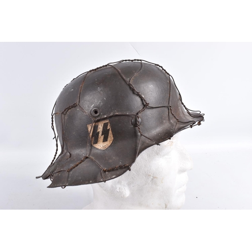 469 - A BATTLE DAMAGED WWII ERA GERMAN STEEL HELMET WITH CAMOUFLAGE WIRE NETTING,  this helmet still has a... 