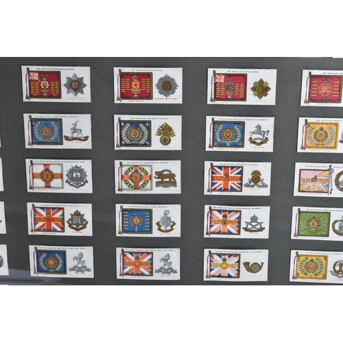 473 - THREE FRAMED AND GLAZED DISPLAYS OF MILITARY CAP BADGES AND KINGS COLOURES, the cards include one fr... 