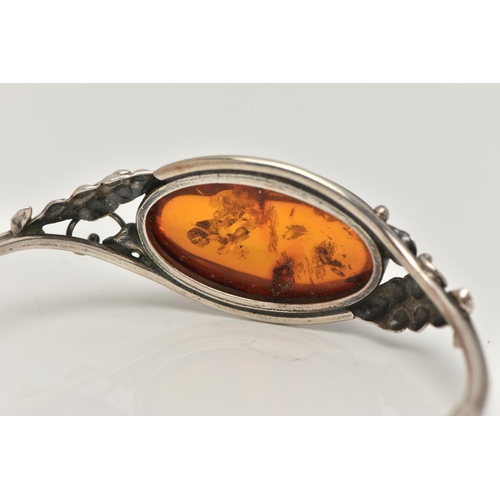 19 - A SILVER AMBER BANGLE, designed as an oval cabochon of heated amber within a collet mount to the bif... 