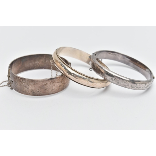 73 - THREE SILVER BANGLES, to include a wide hinged bangle, foliage pattern, push piece clasp, with addit... 