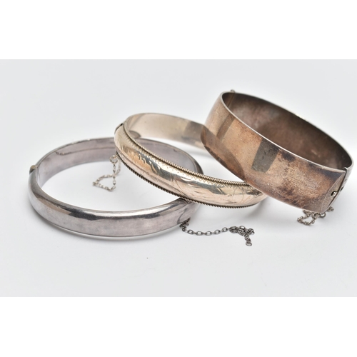 73 - THREE SILVER BANGLES, to include a wide hinged bangle, foliage pattern, push piece clasp, with addit... 