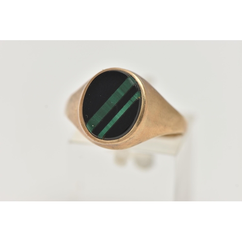 82 - A GENTS 9CT GOLD SIGNET RING, of an oval form, set with an onyx inlay with malachite detail, collet ... 