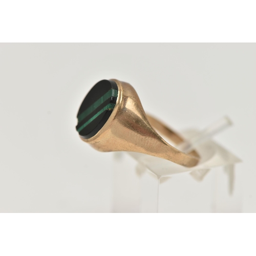 82 - A GENTS 9CT GOLD SIGNET RING, of an oval form, set with an onyx inlay with malachite detail, collet ... 