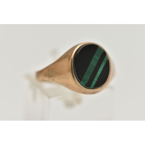 82 - A GENTS 9CT GOLD SIGNET RING, of an oval form, set with an onyx inlay with malachite detail, collet ... 