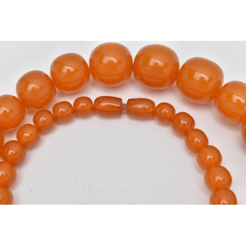 1244A - TWO EARLY TO MID 20TH CENTURY BAKELITE BEAD NECKLACES, the first a single row of circular orange bea... 