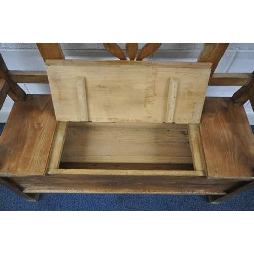 1248 - A 19TH CENTURY STYLE PINE HALL SETTLE, with foliate detail to back and sides and a single hinged sea... 