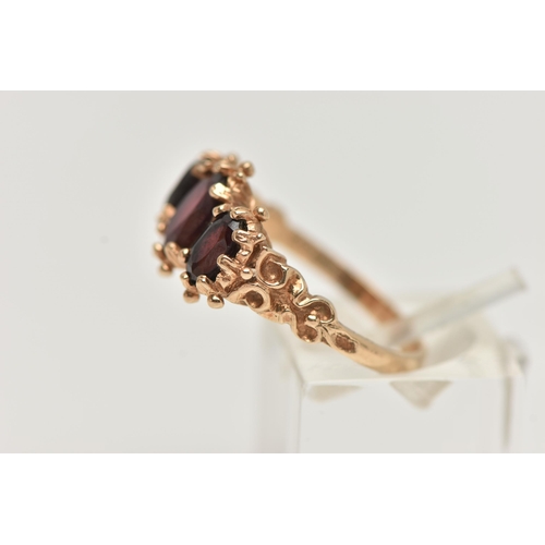 22 - A 9CT GOLD THREE STONE RING, claw set with three oval cut garnets, applied bead work surround, textu... 