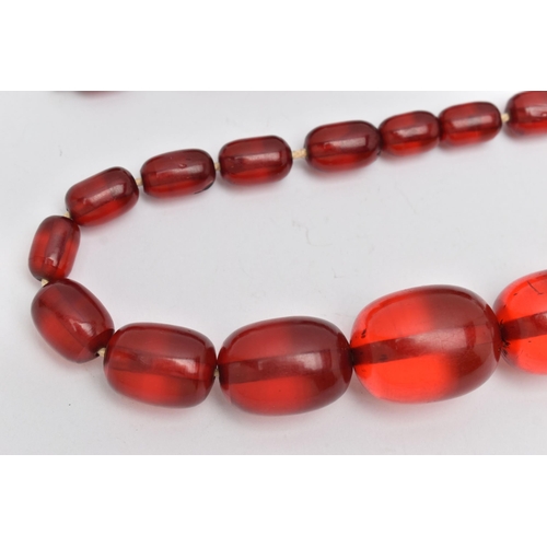 51 - A SINGLE STRAND OF GRADUATED RED PLASTIC BEADS, twenty four oval red beads, largest measuring 29.1mm... 