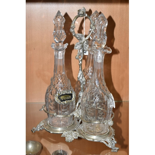 357 - THREE LATE NINETEENTH CENTURY DECANTERS ON A PLATED STAND, the footed stand with foliate decoration,... 