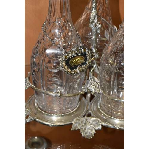 357 - THREE LATE NINETEENTH CENTURY DECANTERS ON A PLATED STAND, the footed stand with foliate decoration,... 