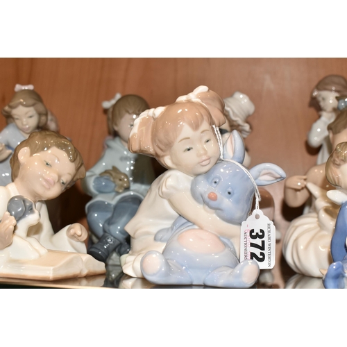 372 - ELEVEN NAO FIGURES OF CHILDREN, to include a boy reading to a puppy, a girl with a toy rabbit, a gir... 