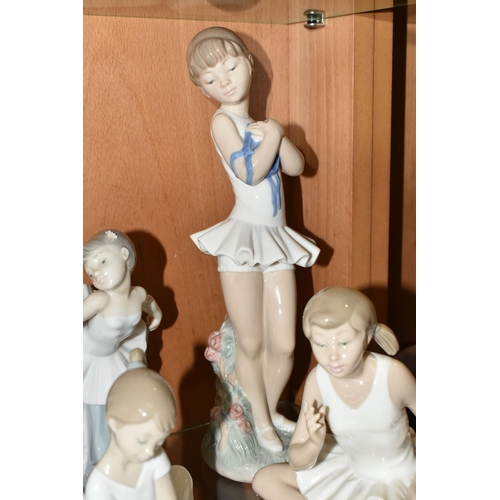 374 - NINE NAO FIGURES OF BALLERINAS, in different poses, tallest standing ballerina holding shoes 29cm, o... 