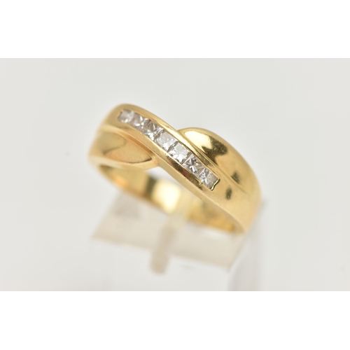 59 - AN 18CT GOLD DIAMOND SET RING, seven princess cut diamonds channel set in yellow gold, cross over mo... 