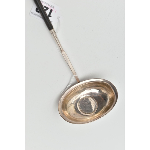 122 - A WHITE METAL LADLE, set with a worn silver coin to the base, fitted with an ebonised handle (condit... 