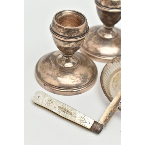 141 - A SELECTION OF SILVERWARE, to include a pair of dwarf candlesticks, a pair of napkin rings, a limite... 