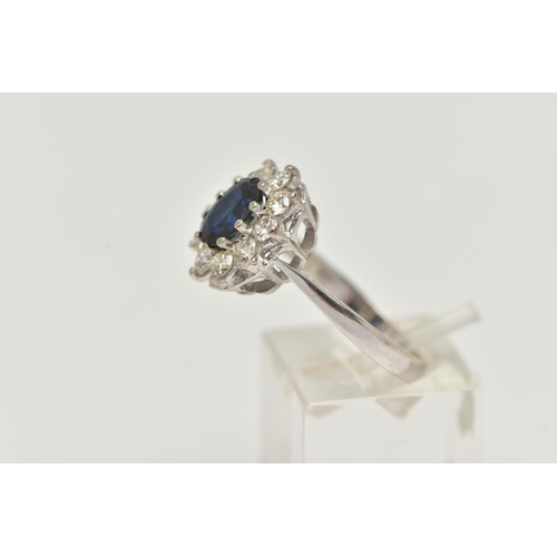 13 - AN 18CT WHITE GOLD SAPPHIRE AND DIAMOND CLUSTER RING, the oval sapphire within a ten claw setting su... 