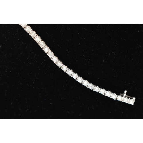 23 - A 9CT WHITE GOLD DIAMOND LINE BRACELET, designed as sixty-four round brilliant cut diamonds each wit... 