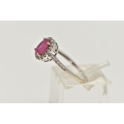 71 - AN 18CT WHITE GOLD RUBY AND DIAMOND RING, set with an oval cut ruby, in a halo of round brilliant cu... 