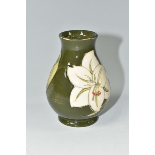 392 - A MOORCROFT POTTERY BALUSTER VASE DECORATED WITH WHITE LILIES ON A GREEN GROUND, impressed marks and... 